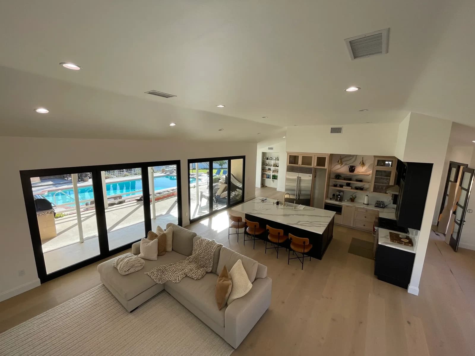 Open-concept great room remodel with vaulted ceilings, waterfall island, and floor-to-ceiling sliders to the pool in Ventura County, CA